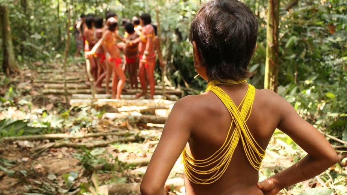 Criança observa grupo na Terra Indígena do Javari, no Amazonas, que sofreu ataque de garimpeiros