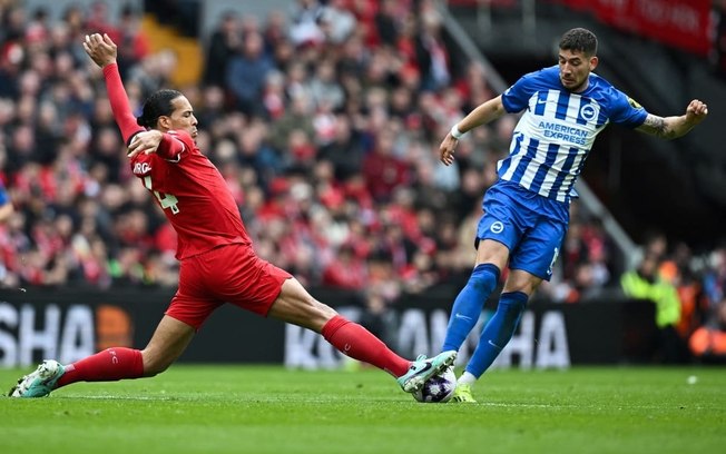 O zagueiro do Liverpool  van Dijk (de vermelho) se estica para dividir a bola com o polonês Moder