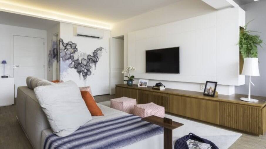 Com um estilo bem moderninho, os puffs desse apartamento dão um toque de cor para dar vida ao ambiente. São dois menores para servir bem a circulação mais estreita, além de serem na altura do sofá para acomodar os pés na hora de assistir TV