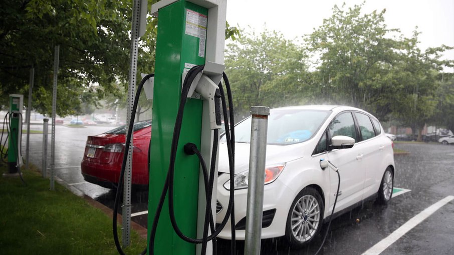 Carro elétrico sendo carregado na chuva