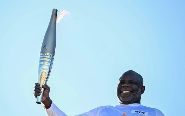 O ex-jogador de futebol Basile Boli exibe a tocha olímpica no início do revezamento pelas ruas da cidade de Marselha