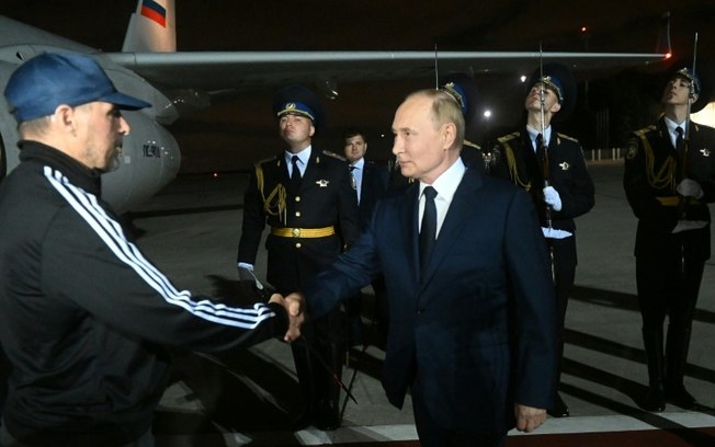 O presidente Vladimir Putin (D) cumprimenta Vadim Krasikov ao chegar ao aeroporto de Vnukovo, em Moscou, em 1º de agosto de 2024