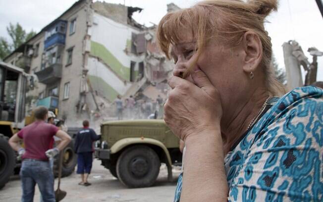 Mulher chora perto de prédio que desmoronou após ataque aéreo em Snizhne, a 100 km a leste da cidade de Donetsk, no leste da Ucrânia (15/07). Foto: AP