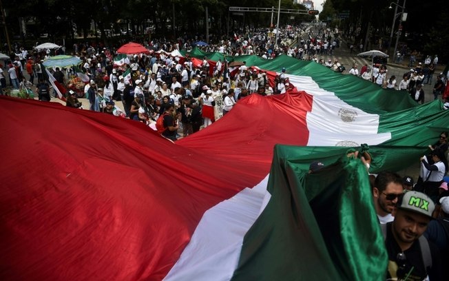 Membros da Associação Nacional de Magistrados e Juízes Distritais seguram uma enorme bandeira mexicana durante um protesto após a aprovação no Senado da reforma do Judiciário, na Cidade do México, em 11 de setembro de 2024