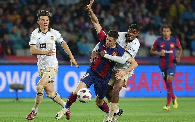 Lewandowski em disputa de bola com jogadores do Valencia - Foto: Lluis Gene/AFP via Getty Images