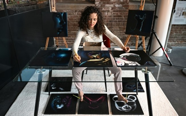 A artista neerlandesa Rajacenna van Dam pinta dez quadros simultaneamente com seus pés e mãos em um museu de Vlaardingen, em 3 de maio de 2024