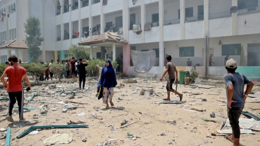 Palestinos caminham entre escombros após bombardeio israelense contra a escola Khadija em Deir al Balah, no centro de Gaza, em 27 de julho de 2024