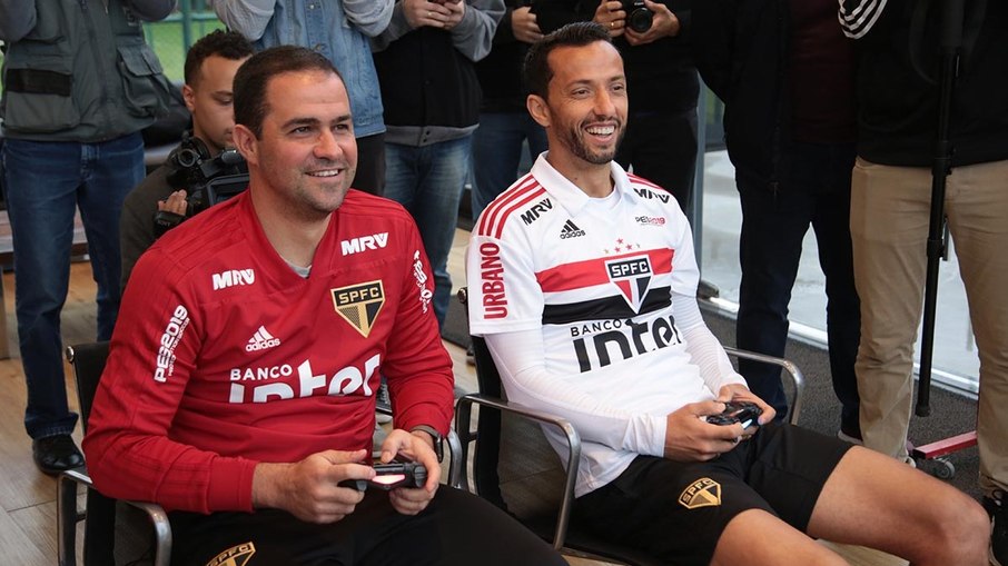 Nenê jogando videogame ao lado de André Jardine