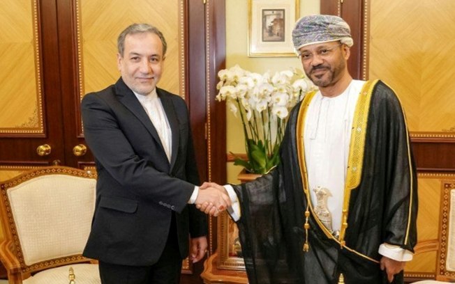 O ministro das Relações Exteriores iraniano, Abbas Araqchi (à esquerda), aperta a mão de seu homólogo de Omã, Sayyid Badr al Busaidi, em 14 de outubro de 2024, em Mascate