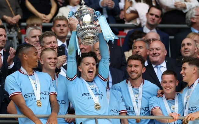 O ponta-esquerda Jack Grealish ergue a taça após o Manchester City conquistar a Copa da Inglaterra em 3 de junho de 2023 em Wembley, Londres