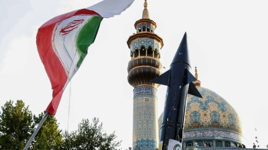 Os iranianos erguem uma bandeira e a maquete de um míssil durante uma celebração após o ataque de mísseis e drones do Irã contra Israel, em 15 de abril de 2024, na praça Palestina, no centro de Teerã