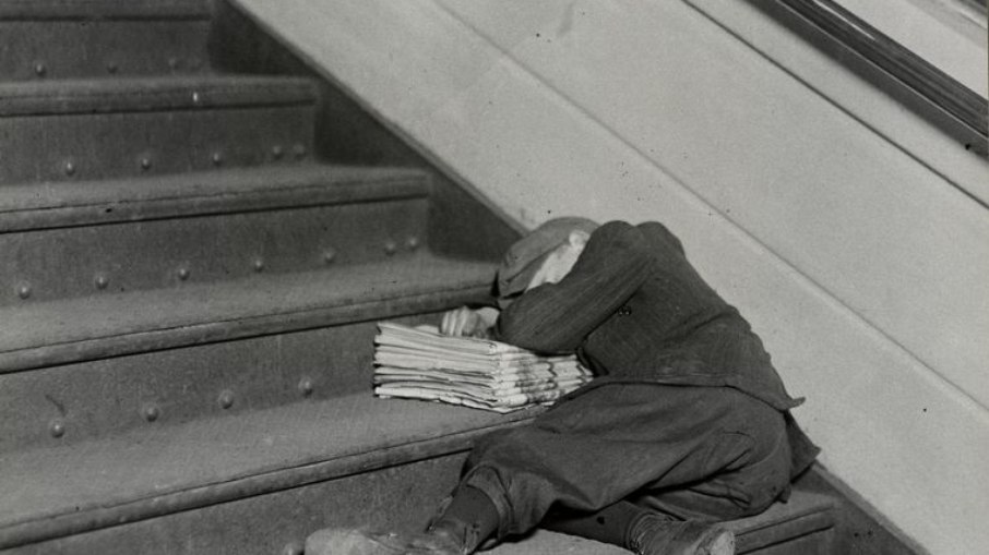 Menino jornaleiro dormindo na escadaria com jornais à noite em Jersey City, Nova Jersey, novembro de 1912.