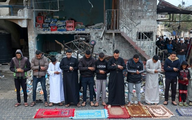 Palestinos deslocados rezam durante o primeiro dia do Eid al-Fitr, feriado que marca o fim do Ramadã, em Rafah, sul da Faixa de Gaza, em 10 de abril de 2024