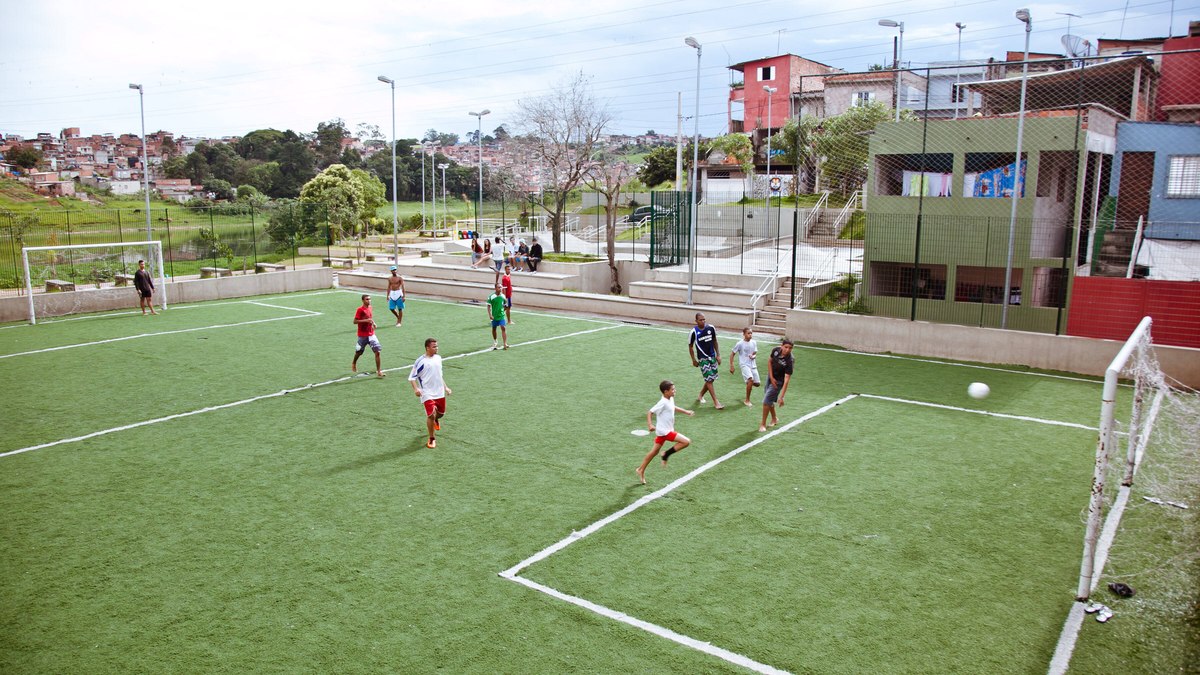 Meninos jogam futebol em quadra com grama sintética Meninos jogam futebol em quadra com grama sintética
