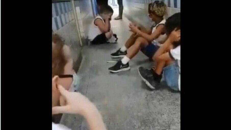 Crianças sentadas no corredor da escola no momento em que acontece um tiroteio na Escola Municipal Sobral Pinto, na Praça Seca, RJ