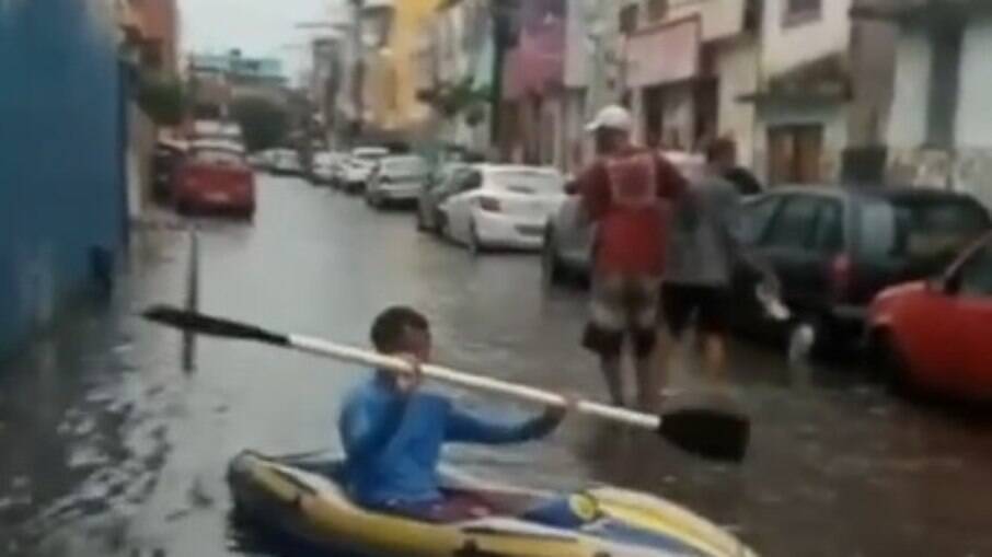 Homem usa caiaque para se locomover em rua alagada