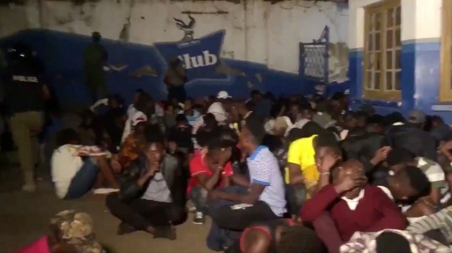 Ugandenses sentados e detidos pela polícia, do lado de fora do Ram Bar, na capital do país, em 2019