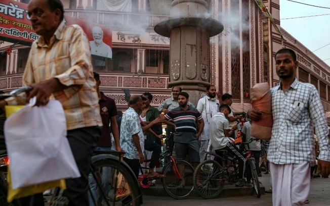 Homens esperam ao lado de um aspersor de água instalado para resfriar um mercado na cidade indiana de Varanasi, em 31 de maio de 2024 Homens esperam ao lado de um aspersor de água instalado para resfriar um mercado na cidade indiana de Varanasi, em 31 de maio de 2024