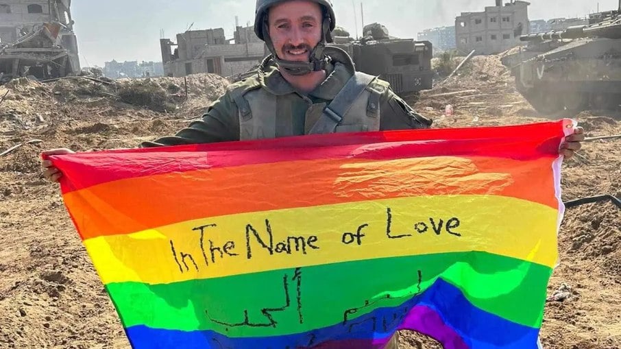 Yoav Atzmoni segurando uma bandeira LGBTQ+ em Gaza, com a frase: ‘Em nome do amor’