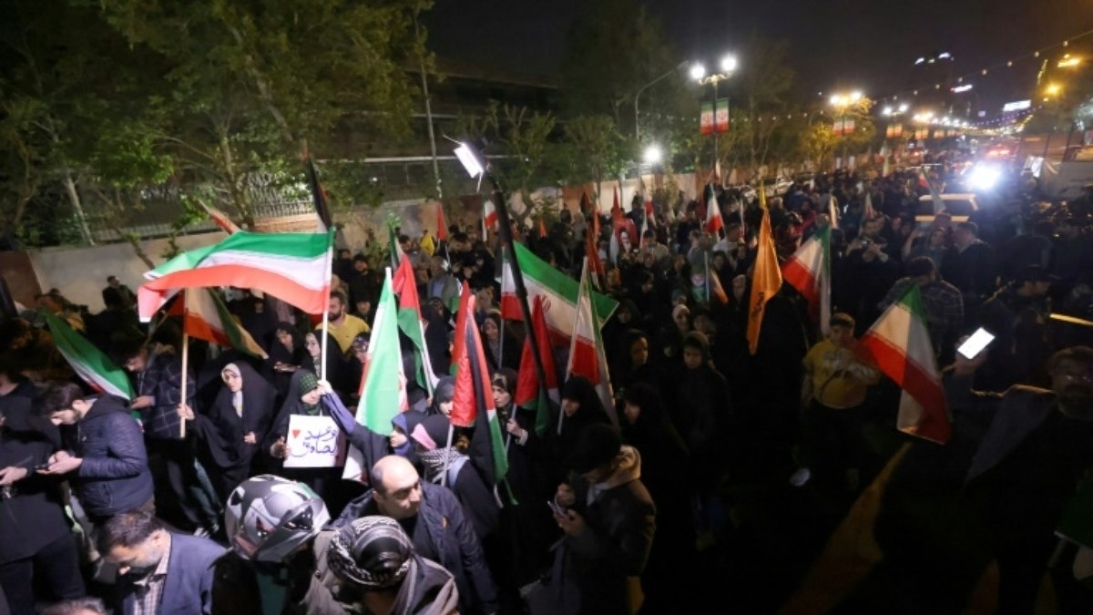 Manifestantes agitam bandeiras iranianas durante concentração em frente à embaixada britânica em Teerã, em 14 de abril de 2024, após um ataque com drones e mísseis lançado por Teerã contra Israel Manifestantes agitam bandeiras iranianas durante concentração em frente à embaixada britânica em Teerã, em 14 de abril de 2024, após um ataque com drones e mísseis lançado por Teerã contra Israel