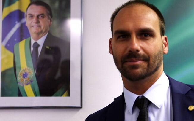 Eduardo Bolsonaro com quadro de seu pai Jair Bolsonaro ao fundo