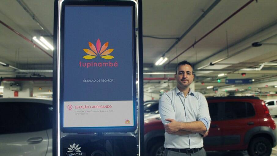 O CEO da startup Tupinambá, Davi Bertoncello, ao lado e um dos carregadores de uso semi-público 