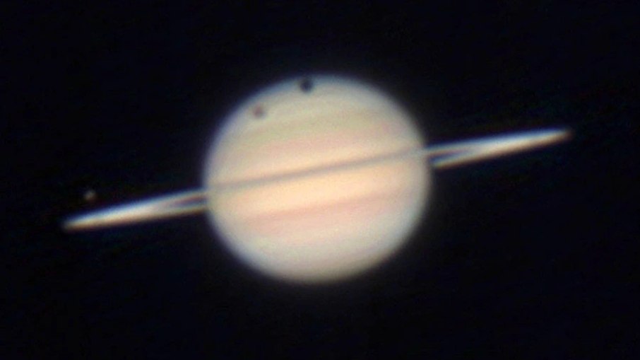 Titã (mancha pálida menor à esquerda) e sua sombra escura cruzam o disco de Saturno em 2009 Titã (mancha pálida menor à esquerda) e sua sombra escura cruzam o disco de Saturno em 2009