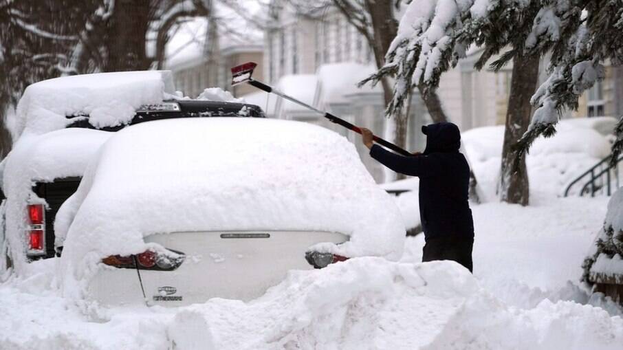 Homem tenta desenterrar carro da nevasca