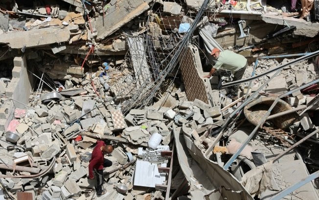 Palestinos entre os escombros de edifício atingido por ataques israelenses no bairro Al Daraj, em Gaza, em 23 de maio de 2024
