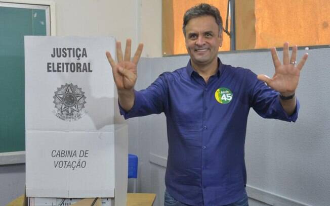 Depois de votar, Aécio Neves, que disputou a Presidência pelo PSDB em 2014, fez pose com seu número para os fotógrafos