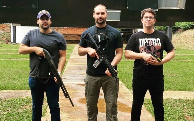 André Porciuncula ao lado de Eduardo Bolsonaro e Mario Frias posando com armas - foto publicada pelo servidor numa rede social