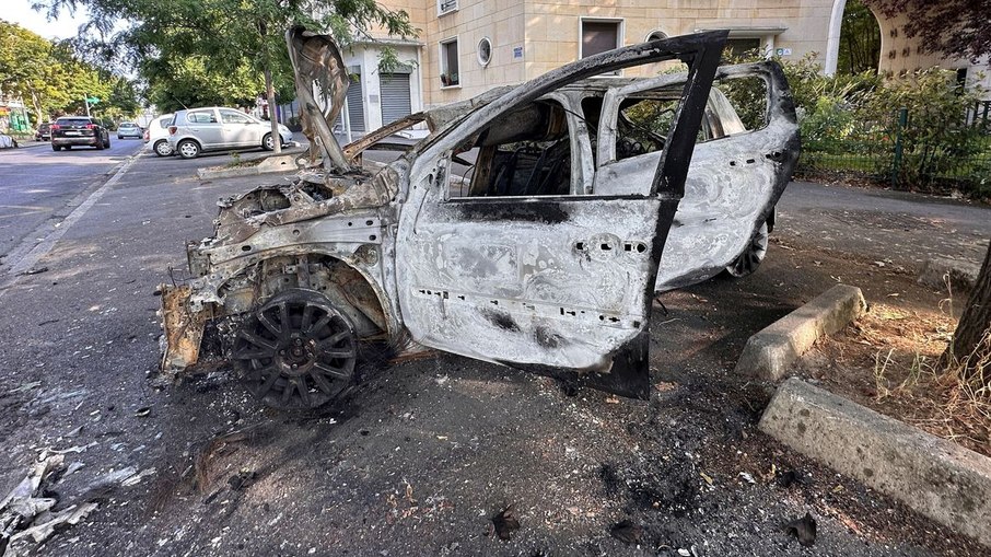 Carro queimado em rua do subúrbio de Paris após confrontos entre a polícia e jovens