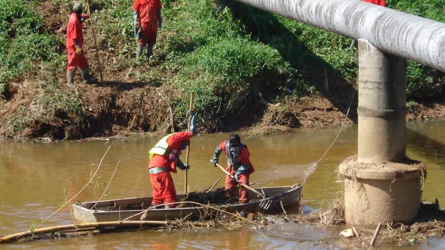 Trabalhadores da empresa de saneamento básico limpam rio