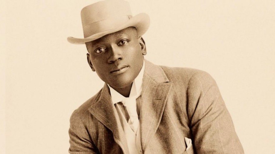 Jack Johnson em 1908, pouco antes de se tornar o primeiro campeão negro dos pesos-pesados. Nesse momento, ele já chamava atenção não apenas pelo talento no ringue, mas também pela postura confiante e pela forma como desafiava os padrões raciais e sociais da época. Jack Johnson em 1908, pouco antes de se tornar o primeiro campeão negro dos pesos-pesados. Nesse momento, ele já chamava atenção não apenas pelo talento no ringue, mas também pela postura confiante e pela forma como desafiava os padrões raciais e sociais da época.