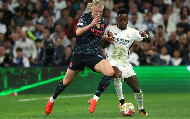 O atacante norueguês do Manchester City, Erling Haaland, disputa com o atacante brasileiro do Real Madrid, Vinicius Junior, durante o jogo de ida das quartas de final da Champions League no estádio Santiago Bernabeu, em Madri, em 9 de abril de 2024.