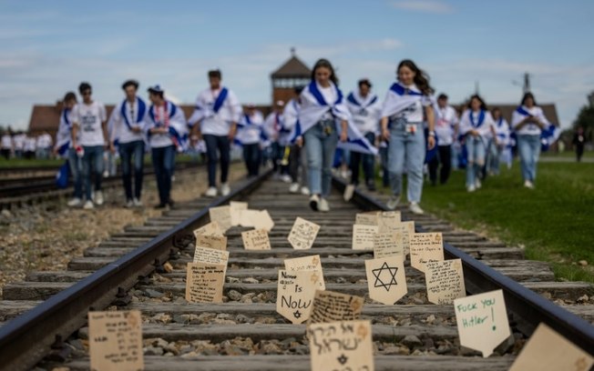 Placas de madeira com mensagens e orações colocadas na linha férrea que leva ao antigo campo de extermínio nazista Auschwitz-Birkenau, Polônia, 6 de maio de 2024