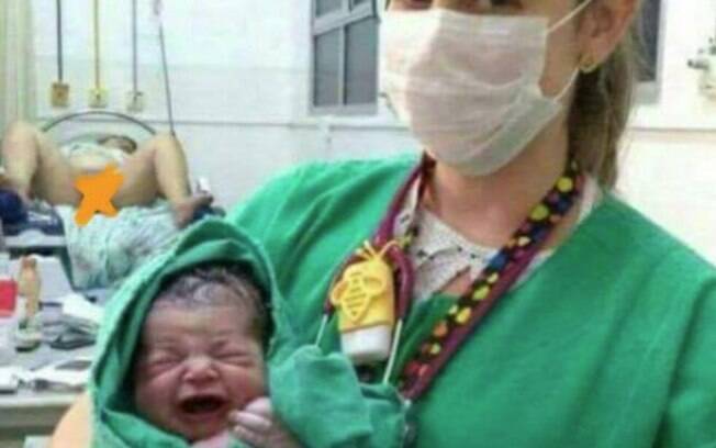 O foco da foto era para ser o recém-nascido, mas a mãe nua e com as pernas abertas ao fundo roubou os holofotes