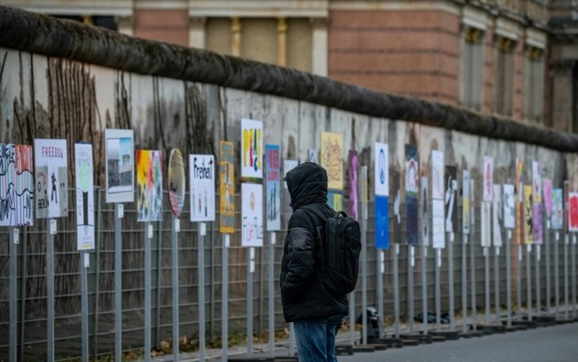 Homem olha para faixas colocadas ao longo da antiga rota do Muro de Berlim na sexta-feira, 8 de novembro, em preparação para as comemorações do 35º aniversário da queda do Muro de Berlim, em 9 de novembro de 1989