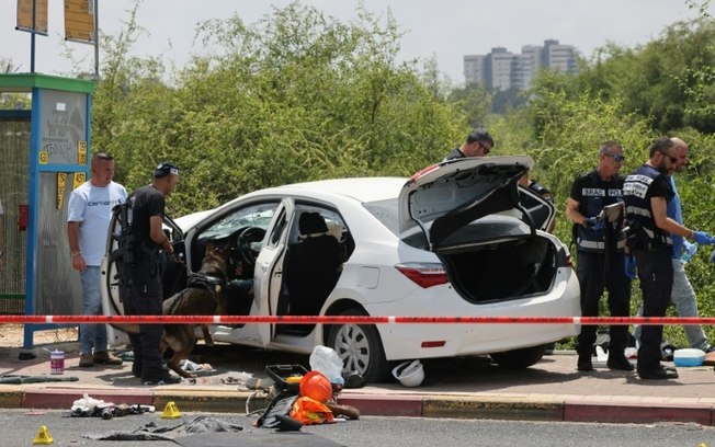 Membros das forças de segurança inspecionam um veículo após um ataque no cruzamento de Nir Zvi, perto de Lod, em 14 de julho de 2024, em Israel