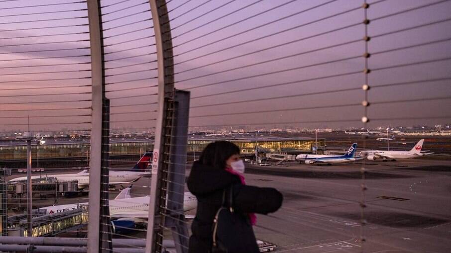 Mulher observa aviões no terminal internacional do aeroporto Haneda, em Tóquio