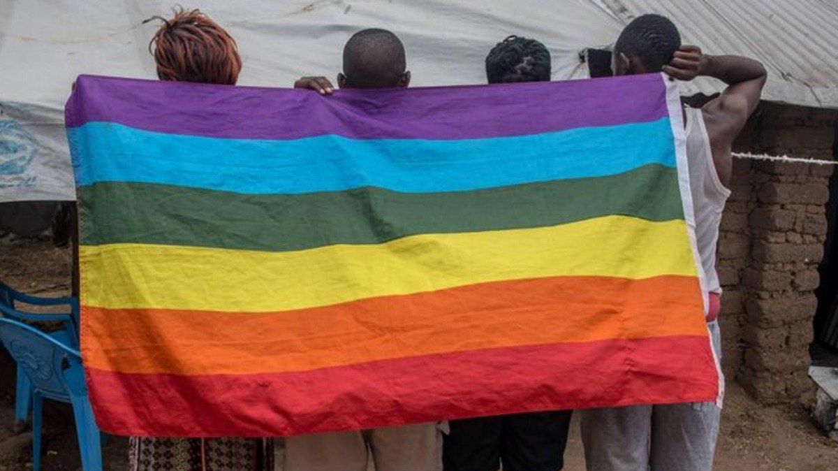 Manifestantes ugandenses pró-LGBT com bandeira do movimento queer