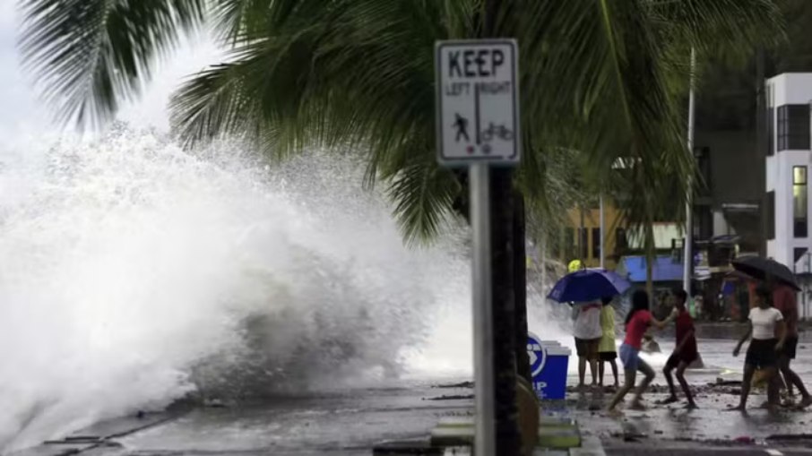 Pessoas reagem enquanto grandes ondas quebram ao longo de um paredão antes da chegada esperada do Super Tufão Man-yi, na cidade de Legaspi, província de Albay, neste sábado (16) 