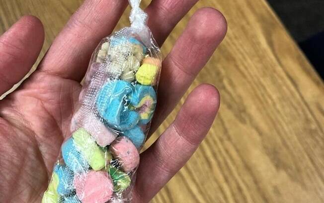 A menina usou a embalagem do seu garfo para colocar os marshmallows do seu cereal e dar para a professora