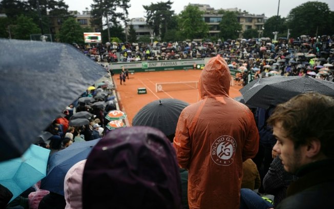 Público tenta se proteger da chuva em uma das quadras de Roland Garros nesta sexta-feira