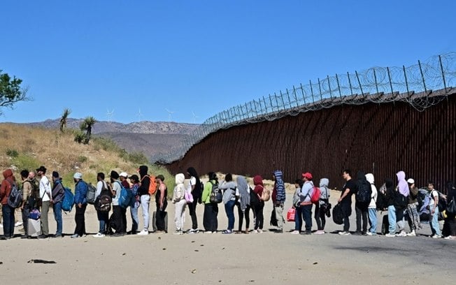 Um grupo de migrantes espera na fila da fronteira entre os EUA e o México, em Jacumba Hot Springs, Califórnia, em 5 de junho de 2024