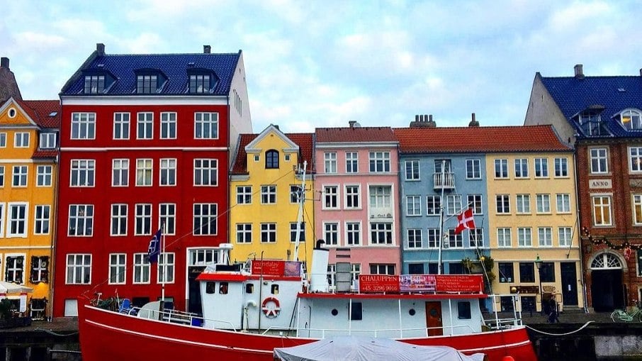 As casas coloridas e o rio que margeia a rua Nyhavn, em Copenhagen, na Dinamarca
