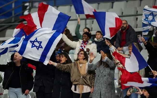 Torcedores franceses e israelenses agitam bandeiras durante jogos entre as seleções dos dois países nesta quinta-feira, no Stade de France, pela Liga das Nações