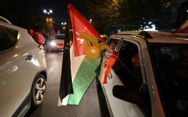 Manifestantes exibem em uma carreata as bandeiras palestina e do Hezbollah, durante uma comemoração em Teerã, após o disparo de mísseis iranianos contra Israel, em 1º de outubro de 2024