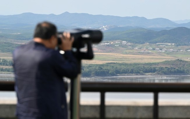 Homem usa binóculos no Observatório de Unificação de Odusan, Coreia do Sul, para observar o lado norte-coreano da Zona Desmilitarizada