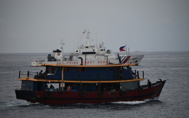 Barco da guarda-costeira das Filipinas escolta embarcações que abastecem um navio da Marinha nas águas disputadas do Mar da China Meridional